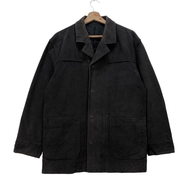 May include: A dark gray workwear jacket with a button-up front, two large pockets, and a collar.