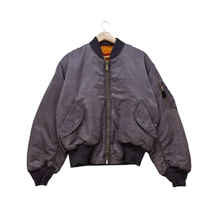 May include: A dark grey bomber jacket with a full zip, two front pockets, and a zipped pocket on the left sleeve. The jacket features black ribbed cuffs and hem. The interior lining is orange. The jacket is hanging on a wooden hanger.