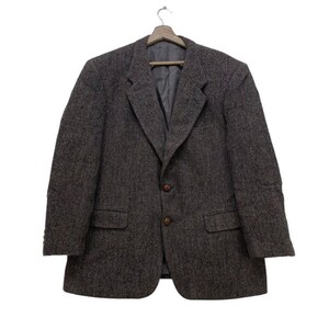 May include: A gray tweed blazer with a single-breasted closure and two button pockets. The blazer has a herringbone pattern and a classic fit.