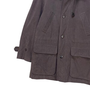May include: A dark gray, long-sleeved jacket with a hood, two large flap pockets, and a button closure.