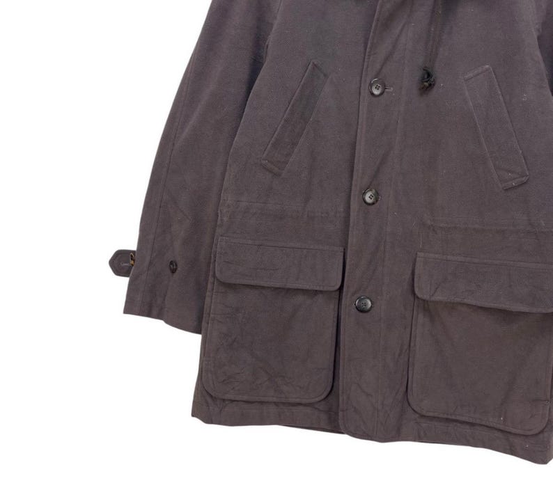 May include: A dark gray, long-sleeved jacket with a hood, two large flap pockets, and a button closure.