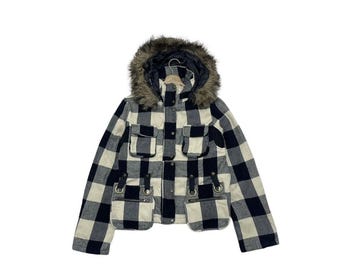 May include: A black and white plaid jacket with a faux fur-lined hood. The jacket has four front pockets, metal ring details, and a button-up closure. The jacket is a winter coat.