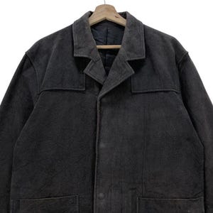 May include: A dark gray long-sleeved jacket with a button-up front and two pockets. The jacket has a collar and a slightly textured fabric.