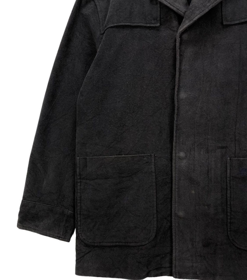 May include: A black long-sleeved jacket with a button-up front and two large pockets. The jacket is made of a thick, textured fabric.