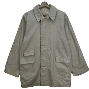 May include: A beige long-sleeved jacket with a button-up front and two large pockets on the front. The jacket has a collar and a single button at the top of the collar.