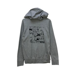 Peut inclure: Un sweat &agrave; capuche gris avec un motif noir et blanc au dos. Le motif est un motif r&eacute;p&eacute;titif de personnages de dessins anim&eacute;s avec de grands yeux et des X &agrave; la place des yeux. Le sweat &agrave; capuche a une capuche &agrave; cordon et une poche avant.
