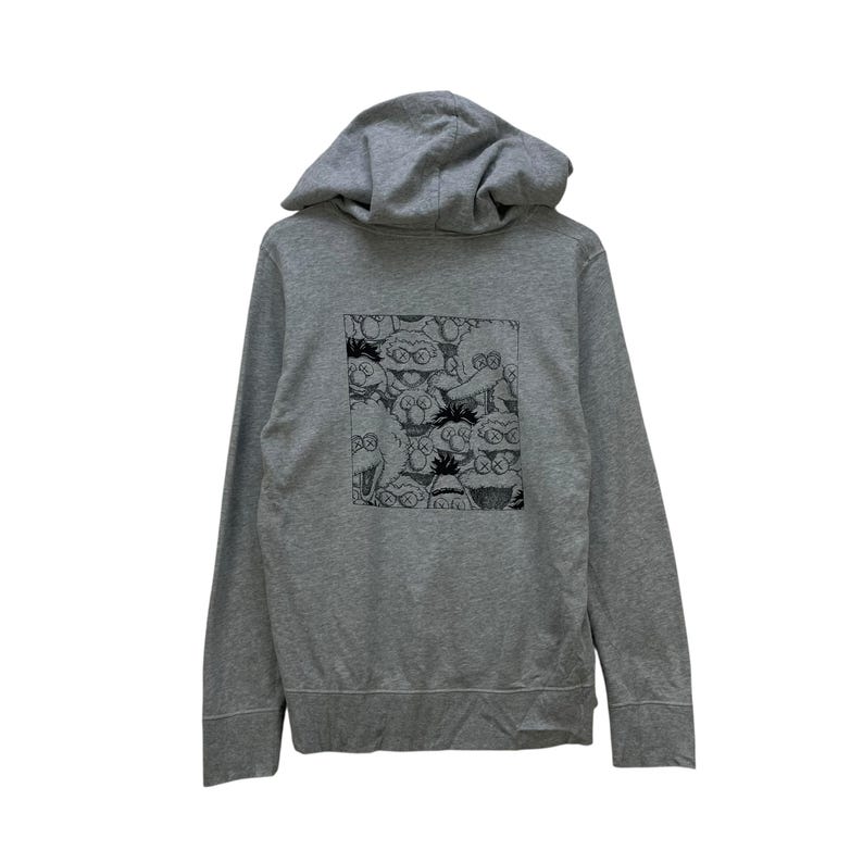 Peut inclure: Un sweat &agrave; capuche gris avec un motif noir et blanc au dos. Le motif est un motif r&eacute;p&eacute;titif de personnages de dessins anim&eacute;s avec de grands yeux et des X &agrave; la place des yeux. Le sweat &agrave; capuche a une capuche &agrave; cordon et une poche avant.
