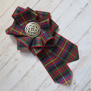 May include: A red, green, blue, and yellow plaid ribbon bow with a silver Celtic knot design brooch.