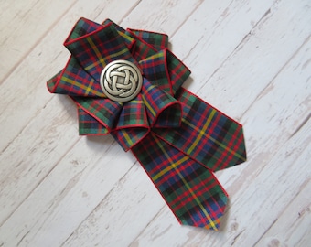 Può includere: Un fiocco di nastro tartan rosso, verde, blu e giallo con una spilla in argento con design a nodo celtico.