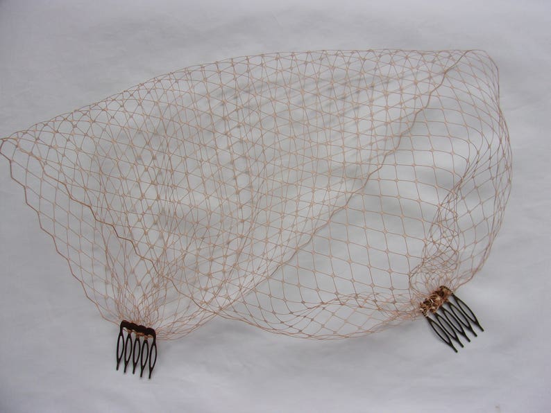 May include: A blush-colored bridal veil with a fine mesh pattern and two combs attached.