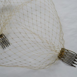 May include: A beige bridal veil with two gold combs attached.