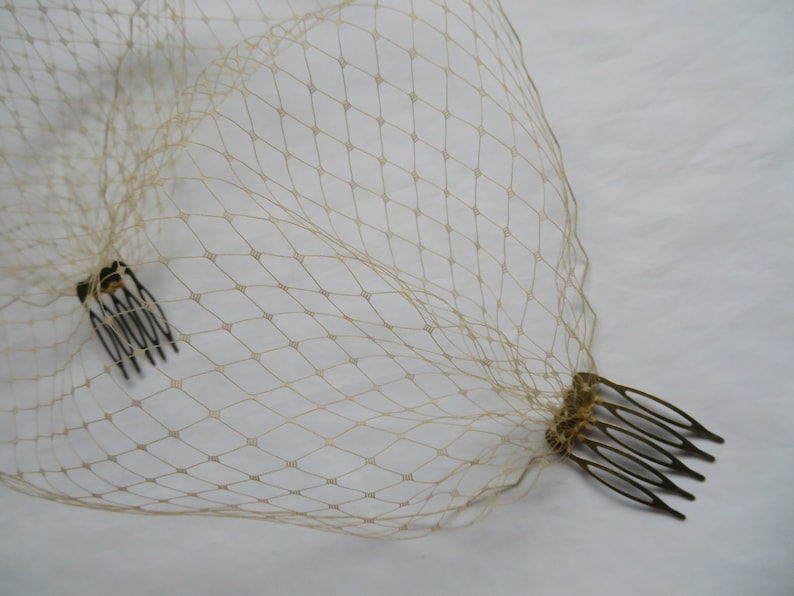 May include: A beige bridal veil with two gold combs attached.