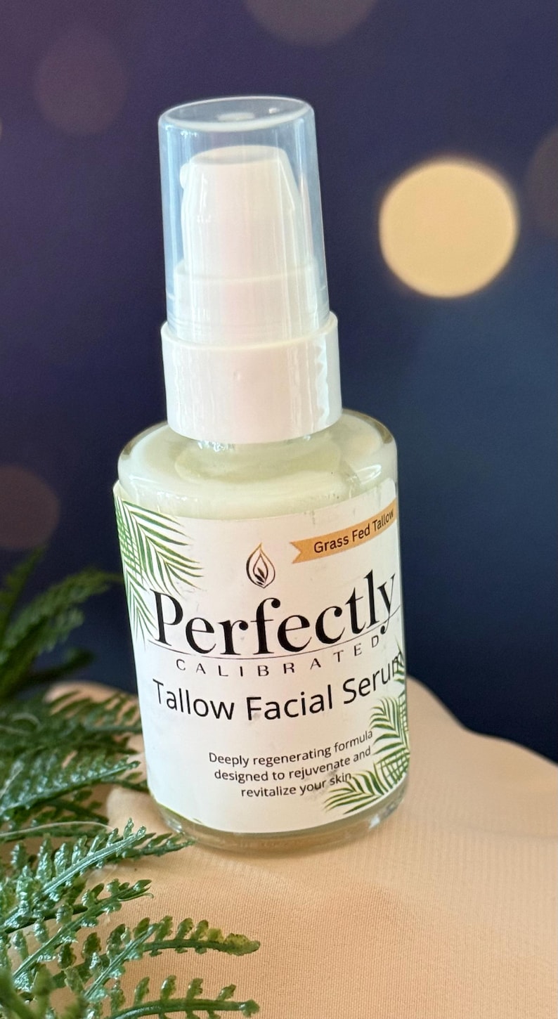 May include: A clear glass bottle of Perfectly Calibrated Tallow Facial Serum with a white pump top. The label includes text and a palm frond design. The words "Grass Fed Tallow" are also visible.