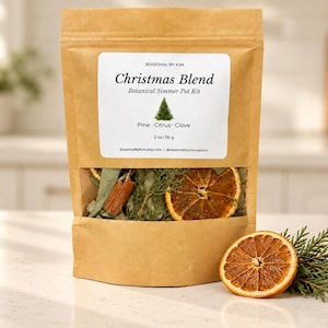 May include: A brown paper pouch containing a Christmas Blend botanical simmer pot kit with pine, citrus, and clove. The label displays the text Seasonal by Kim, Christmas Blend, Botanical Simmer Pot Kit, Pine, Citrus, Clove, and 2 oz | 56 g.