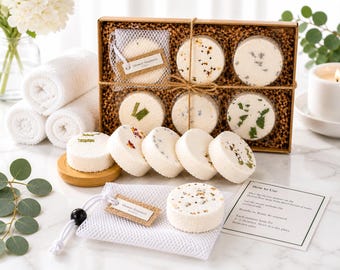 May include: A set of round white shower steamers with botanical inclusions, packaged in a brown cardboard box with shredded paper filler. Includes a white mesh drawstring bag, a wooden base, and an instructional card labeled How to Use.