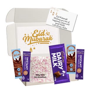 May include: A gift box containing hot chocolate sachets, a Cadbury Dairy Milk chocolate bar, and a bag of marshmallows. The box is decorated with "Eid Mubarak" and a greeting card.