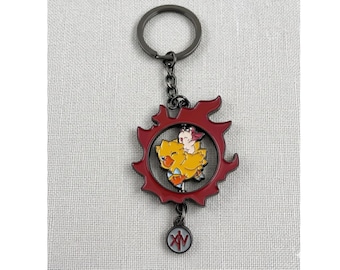 May include: A red and yellow Final Fantasy XIV keychain. The keychain features a red emblem with a yellow Chocobo and a small character inside. A small charm with the letters "XIV" hangs below.