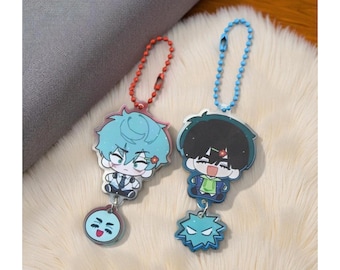 May include: Two anime-style keychains. One keychain has a red chain and features a character with blue hair and a flower. The other has a blue chain and a character with black hair. Both have a charm at the bottom.