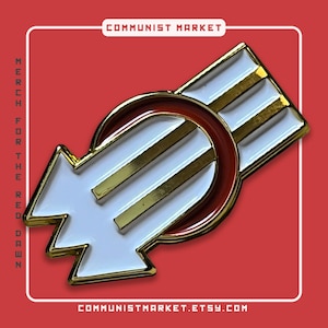 May include: A gold and red enamel pin featuring a white arrow pointing to the right, with three gold stripes and a red circle around the arrow. The pin reads "COMMUNIST MARKET" at the top and "COMMUNISTMARKET.ETSY.COM" at the bottom.