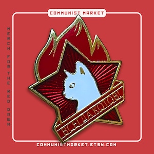 Puede incluir: Un pin de esmalte rojo con borde dorado, que presenta una silueta de gato blanco dentro de una estrella roja con un diseño de llama. El texto "ВСЕГДА КОТОВ!" está escrito en una pancarta dorada.