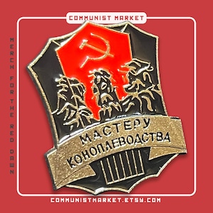 May include: A black and gold enamel pin with a red communist star and hammer and sickle. The pin features a banner with the text "МАСТЕРУ КОНОПЛЕВОДСТВА" in Cyrillic script.