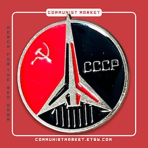 Pode incluir: Um pin redondo vermelho, preto e prateado com o texto "CCCP" e um símbolo de foice e martelo. O pin tem o texto "COMMUNIST MARKET", "MERCH FOR THE RED DAWN" e o endereço do site "COMMUNISTMARKET.ETSY.COM".