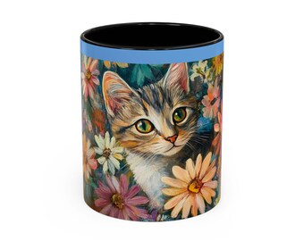 May include: A black ceramic mug with a light blue band around the top. The mug features a colorful illustration of a cat peeking out from behind a bouquet of flowers.