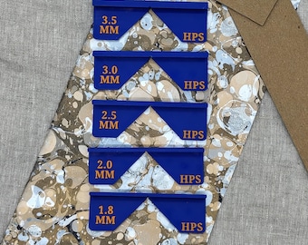 May include: A close-up of five blue, geometric tools with the text "3.5 MM", "3.0 MM", "2.5 MM", "2.0 MM", and "1.8 MM". Each tool has the text "HPS". The tools are on a patterned surface.
