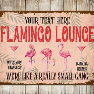May include: A distressed metal sign with a pink backdrop and a brown frame. It displays the words "FLAMINGO LOUNGE" in red, with images of pink flamingos and cocktail glasses. Text includes "WE'RE MORE THAN JUST" and "WE'RE LIKE A REALLY SMALL GANG."