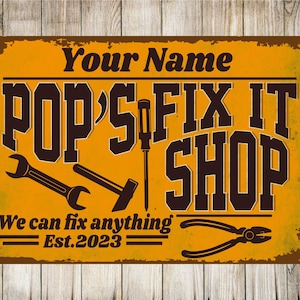 May include: A yellow and brown vintage-style sign with the text "Pop's Fix It Shop" in black lettering. The sign also includes the text "We can fix anything" and "Est. 2023". The sign features various tools, including a wrench, hammer, screwdriver, and pliers.