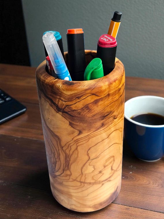 Olive wood has a wild grain and warm honey-green tone unlike any other wood — this pen holder is one of those small desk objects that genuinely looks like it came from somewhere interesting.