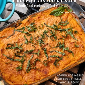 Può includere: Un primo piano di una pirofila con un topping dorato e croccante di formaggio. La pirofila è guarnita con erbe fresche verdi e si trova su un piano cottura. Il testo "FROM SCRATCH Whole food recipes to fuel your day BY CHEF CASEY" è in alto nell'immagine. Il testo "HOMEMADE MEALS FOR EVERY TABLE - WHOLE FOOD VEGAN, AND MEATY DELIGHTS" è in basso nell'immagine.