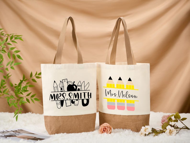 May include: Two canvas tote bags with beige handles and a brown bottom. One bag features the text "MRS. SMITH" with school-themed graphics. The other bag displays "Mrs. Nelson" with pencil graphics. Both bags are on a beige background.