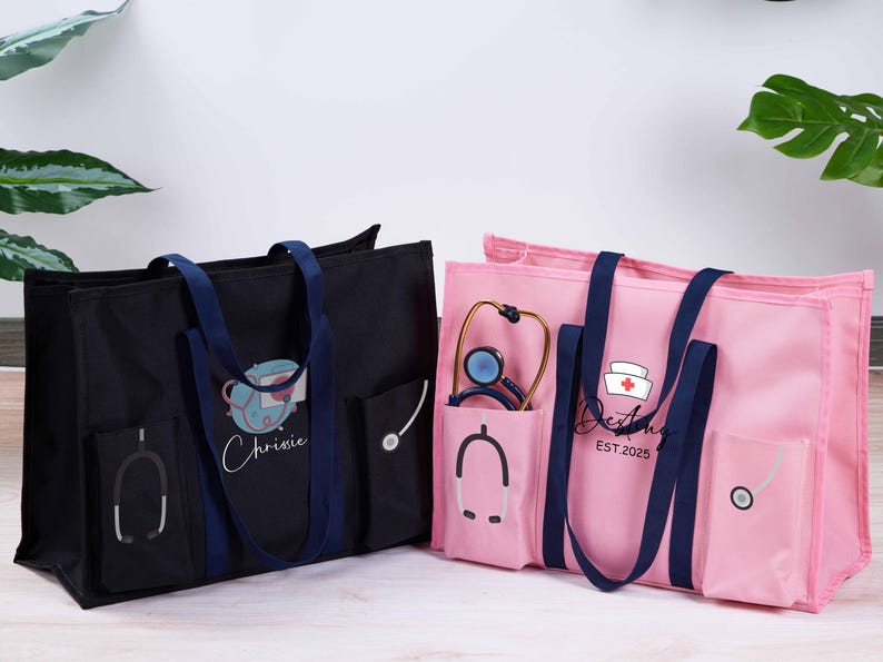 May include: Two tote bags, one black and one pink, with navy blue handles and pockets. The black bag has a medical-themed design with the name "Christie". The pink bag features a nurse's cap and the name "Destiny" with the year 2025.
