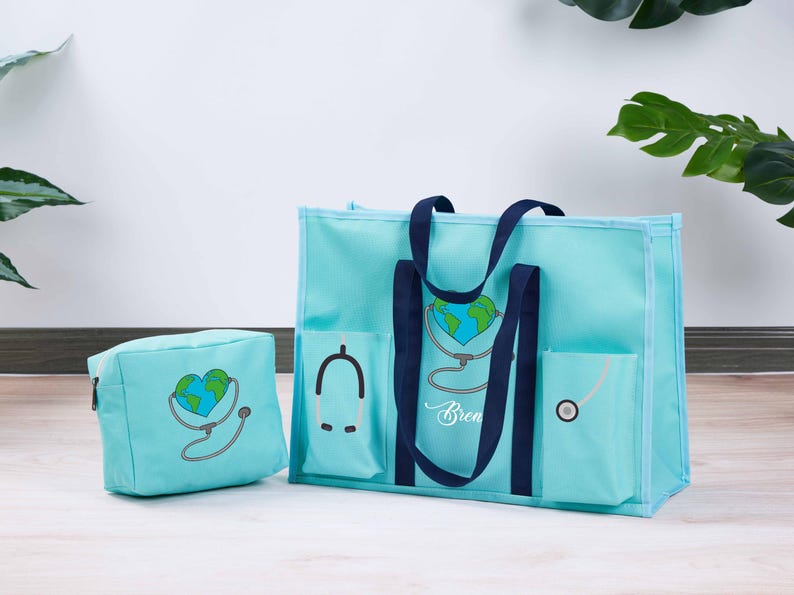 May include: A light blue tote bag and matching cosmetic bag. Both feature a heart-shaped Earth design with a stethoscope. The tote has navy blue handles and pockets. The cosmetic bag has a zipper closure. The word "Brea" is written on the tote.