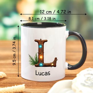 Peut inclure: Mug en c&eacute;ramique blanche avec une anse et un bord noirs, orn&eacute; d'une lettre "L" d&eacute;corative en bois avec des lumi&egrave;res et de la verdure. Le mug mesure 9,5 cm de haut, 12 cm de large et 8,1 cm de diam&egrave;tre. Le nom "Lucas" est imprim&eacute; en dessous.