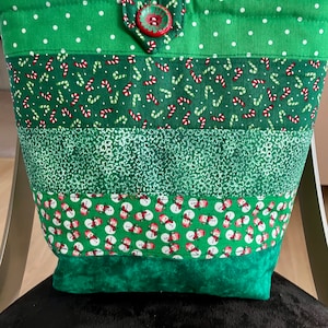 Bolso de mano Doodaba hecho a mano con diseño navideño de campanas verdes, muñecos de nieve y bastones de caramelo.