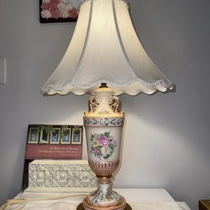 Stara ceramiczna lampa stołowa w kształcie urny z dekoracjami kwiatowymi.