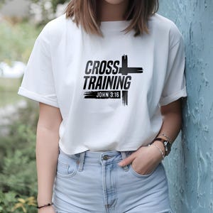 May include: White t-shirt with black text that reads "Cross Training" and "John 3:16". The text is stylized with a black cross graphic.