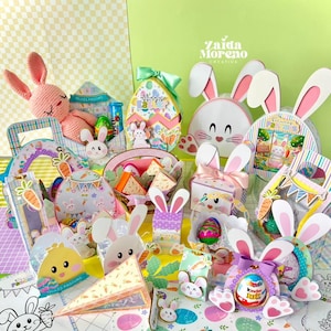 Può includere: Una collezione di decorazioni e regali a tema pasquale, tra cui scatole a forma di coniglietto, contenitori a forma di uovo e un coniglietto all'uncinetto rosa. Gli articoli sono decorati con colori pastello, carote e immagini pasquali. Il testo "Felices Pascuas" è visibile.