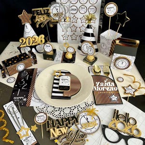 Puede incluir: Una mesa festiva de Nochevieja con decoraciones doradas, negras y blancas. Incluye relojes, adornos en forma de estrella y el texto "Happy New Year" y "2026". Suministros para fiestas temáticas.