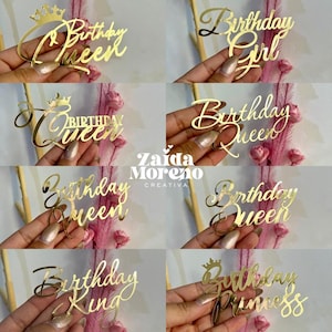 Puede incluir: Adornos para tartas de acrílico dorado con varias frases temáticas de cumpleaños. Los adornos incluyen "Birthday Queen", "Birthday Girl", "Birthday King" y "Birthday Princess". Algunos adornos presentan un diseño de corona. También es visible la marca "Zaida Moreno Creativa".