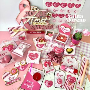 Puede incluir: Una colección de artículos con temática rosa y blanca, que incluyen cajas de regalo, pegatinas y elementos decorativos. Los artículos presentan motivos de corazón y cinta, con texto en español. También hay una cinta rosa y un letrero que dice "Octubre Rosa".