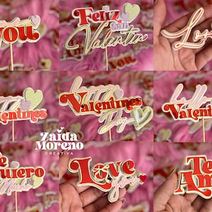 Puede incluir: Surtido de toppers para tartas con temática de San Valentín con varias frases en español e inglés. Los toppers están hechos de cartulina roja, dorada y blanca con detalles de purpurina. Las frases incluyen "Feliz San Valentin", "Love You", "Te Quiero Mucho", "Te Amo", "Happy Valentines Day", "Love You" y "Hello Valentines".