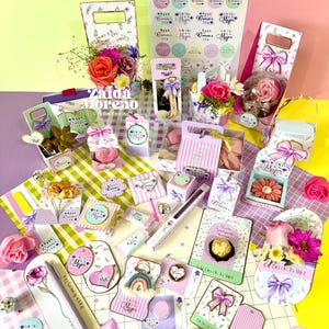 May include: A white ceramic mug with a black handle and the text "But First, Coffee" in a black, handwritten-style font. The mug is on a white surface.