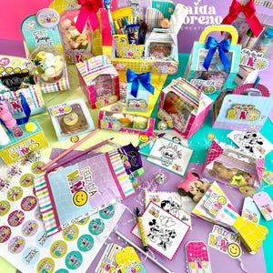 Peut inclure: Un assortiment color&eacute; de bo&icirc;tes cadeaux, d'&eacute;tiquettes et d'autocollants avec le texte "Feliz D&iacute;a Ni&ntilde;@" et des visages souriants. Les bo&icirc;tes, d&eacute;cor&eacute;es de rubans, contiennent des friandises et de petits jouets. Le th&egrave;me est une c&eacute;l&eacute;bration.