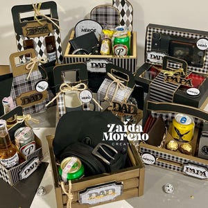 Pode incluir: Uma coleção de conjuntos de presente em caixas de madeira e suportes de cartão pretos e dourados, com latas de cerveja, garrafas, bonés pretos, cintos, carteiras e chocolates, com etiquetas com os dizeres DAD, PAPA e HERO.