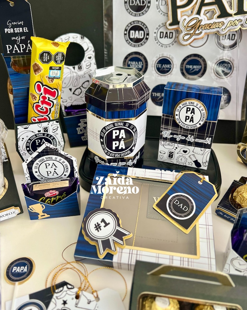May include: An assortment of Father's Day gifts, including a can-shaped container, gift boxes, and tags. The items feature blue and gold accents, with text that reads "DAD" and "PA PA". There is also a candy bar.