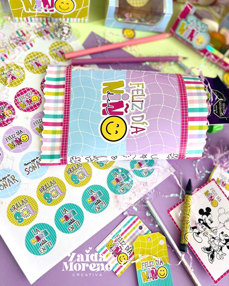 Peut inclure: Une collection de papeterie et d'articles cadeaux color&eacute;s, comprenant des autocollants, des &eacute;tiquettes et un paquet emball&eacute;. Les articles pr&eacute;sentent le texte "Feliz D&iacute;a Ni&ntilde;o" et des graphiques de smiley. Des crayons et d'autres &eacute;l&eacute;ments d&eacute;coratifs sont &eacute;galement visibles.