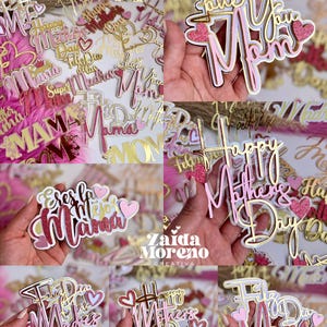 May include: Various cake toppers in pink, gold, and white, designed for Mother's Day. The toppers display messages such as "Love You Mom" and "Happy Mother's Day." Some have glitter and heart decorations.